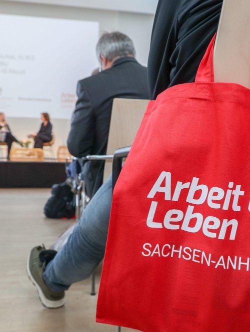 Blick in eine Veranstaltung von Arbeit und Leben Sachsen-Anhalt mit Fokus auf einen Beutel mit Logo.